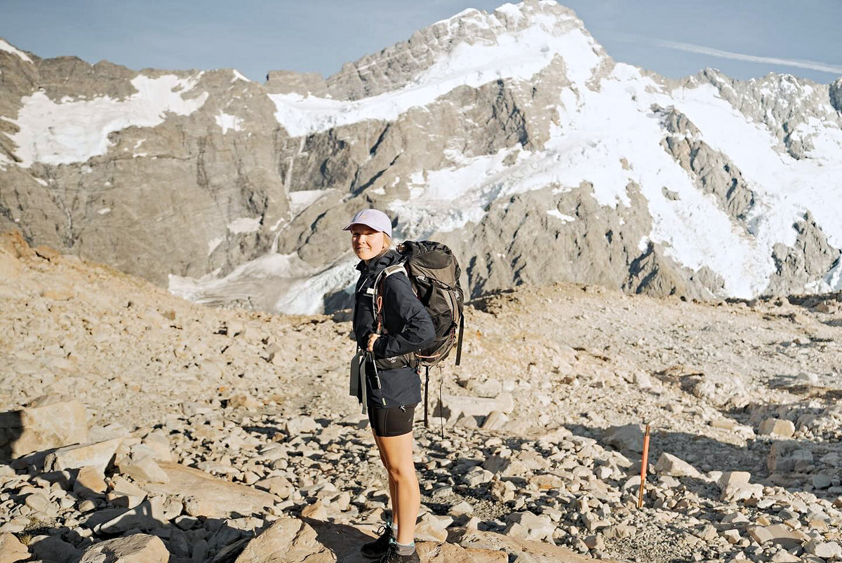 Hiker wearing a lavender Helios cap in an alpine landscape