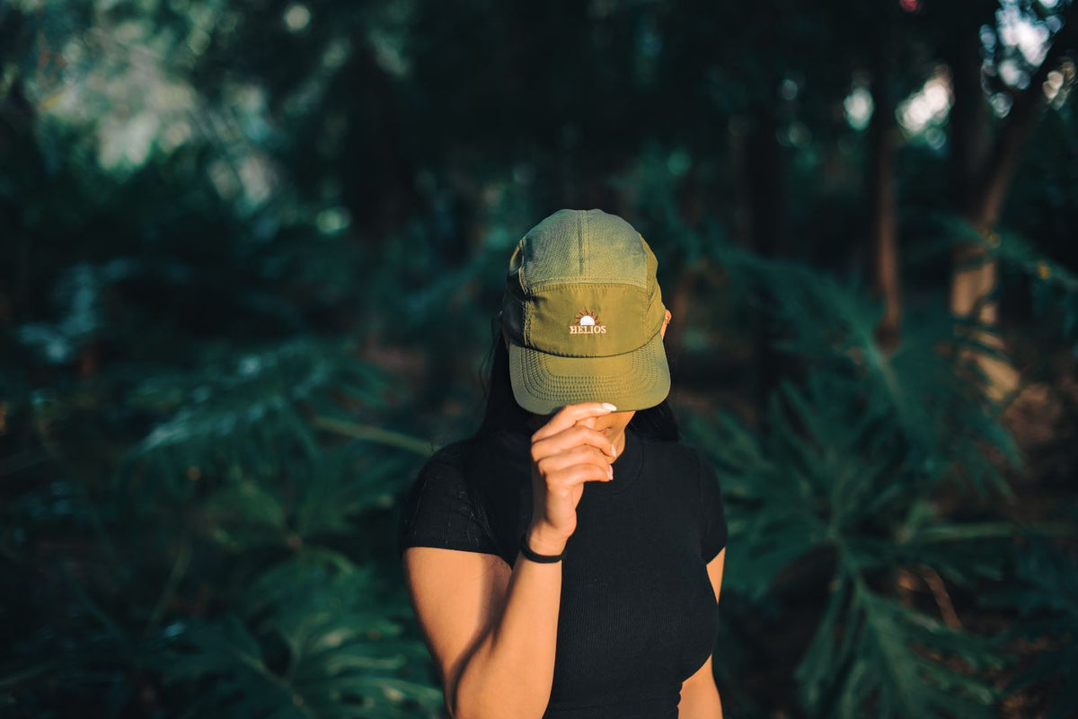 Woman wearing an olive Helios Ultralight cap in a forest