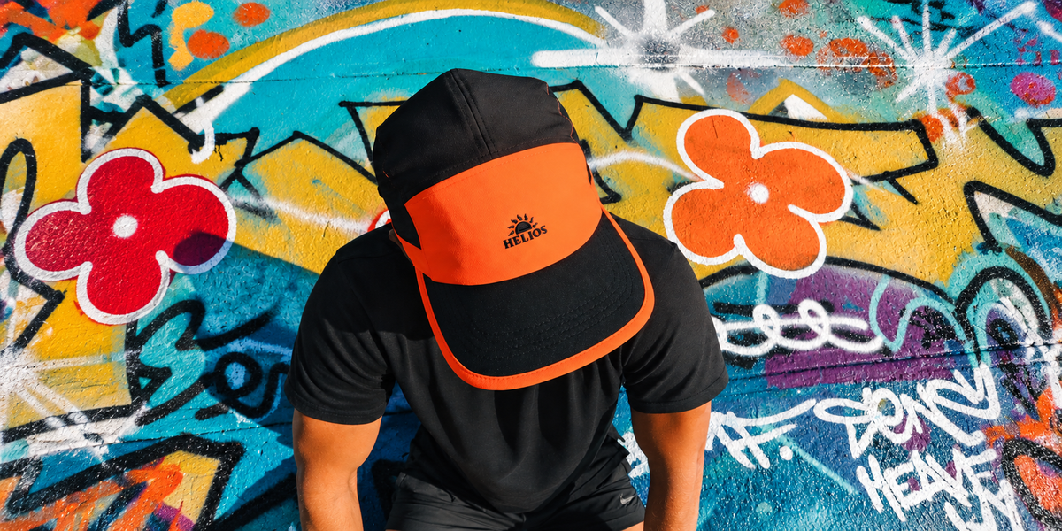 Orange Helios SpeedLid worn against colourful graffiti, enhanced with AI-extended scene for full-bleed framing